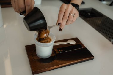 Bardağa soğuk taze süt döken bir kadın baristanın yakın çekimi. Sürecin Kirli Latte Kahve Kremalı Kupasını Yapması