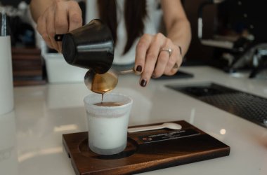Bardağa soğuk taze süt döken bir kadın baristanın yakın çekimi. Sürecin Kirli Latte Kahve Kremalı Kupasını Yapması