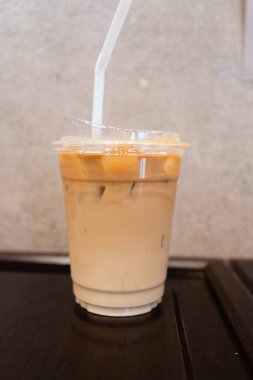 Ahşap arka planda, cam bir fincanda buzlu kahve.