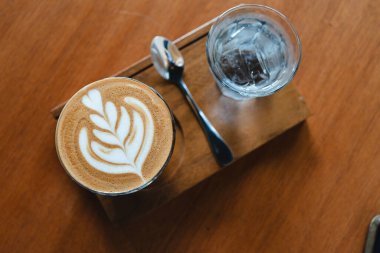 Köpüklü kahve ve ahşap masada su..