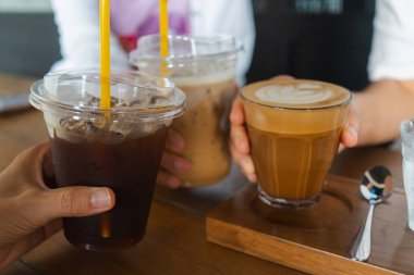 Kafede bir bardak buzlu kahve taşıyan genç kızların elleri..