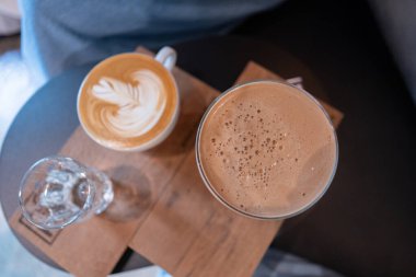 Beyaz bardakta, ahşap masada, sütlü kahvenin en iyi manzarası.