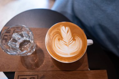 Beyaz bardakta, ahşap masada, sütlü kahvenin en iyi manzarası.