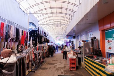 Taşkent, Özbekistan, 28 Ekim 2025. Alışverişçilerin malları karıştırdığı, giysi, yiyecek ve poşet satan renkli, geleneksel bir market. Yüksek kalite fotoğraf