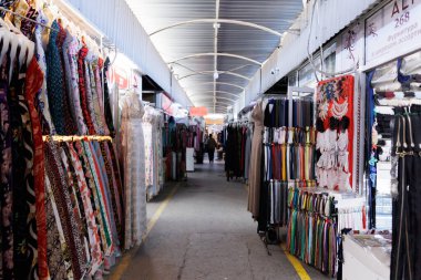 Taşkent, Özbekistan, 28 Ekim 2025. Çok çeşitli kumaş ve giysi sunan, müşterilerin ürünlere göz attığı renkli, geleneksel bir pazar. Yüksek kalite fotoğraf