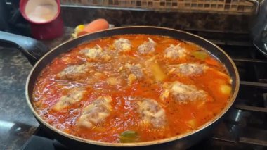 Yemek pişirirken tavada sıcak domates sosunda pişen köfteleri gösteren yakın plan bir video. Yüksek kaliteli FullHD görüntüler
