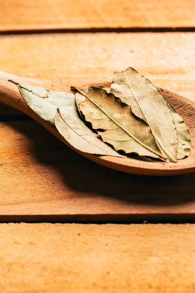 Hoja de laurel en una cuchara de madera clara de cerca —  Fotos de Stock