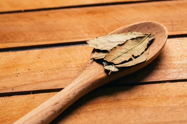 Hoja de laurel en una cuchara de madera clara de cerca —  Fotos de Stock
