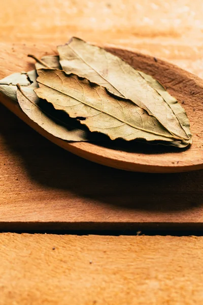 Hoja de laurel en una cuchara de madera clara de cerca —  Fotos de Stock