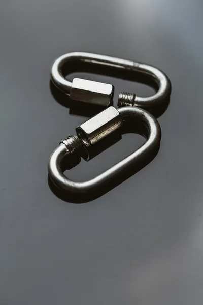 two metal carabiner clip on a dark background