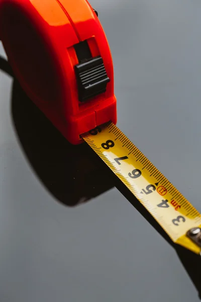 orange construction tape measure against a dark background