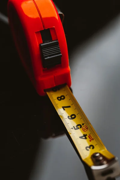 orange construction tape measure against a dark background