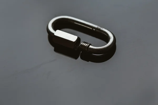 One metal carabiner on a dark background — Stock Photo, Image