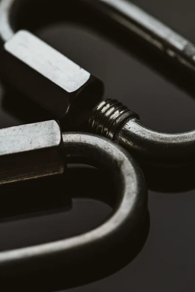 two metal carabiner clip on a dark background