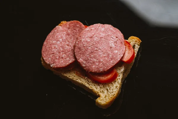 A sötét háttéren füstölt kolbász szendvics Stock Fotó