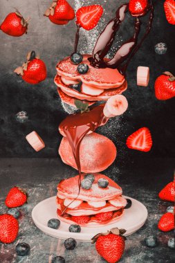 Havada yakalanmış çilekli ve muzlu gözleme. Renk, tazelik ve enerji dolu hareketli lezzetli kahvaltı öğelerini gösteren dinamik ve eğlenceli bir yemek tasarımı konsepti..