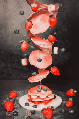 Havada yakalanmış çilekli ve muzlu gözleme. Renk, tazelik ve enerji dolu hareketli lezzetli kahvaltı öğelerini gösteren dinamik ve eğlenceli bir yemek tasarımı konsepti..