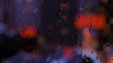 Pencereden damlayan yağmur damlacıkları karanlık bir arka plana ayarlanmış..