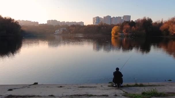 釣り棒を使って漁師のシルエットでダイナミックな夕日のシーンと公園の湖でリラックスします 穏やかな水面を反映したカラフルな木々が美しい秋の季節 — ストック動画
