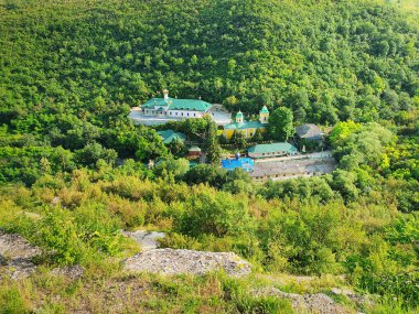 Yükseklikten Moldova 'daki Sahra Manastırı' na yüksek açılı görüş. Ormanın ortasındaki vadide kilisesi olan huzurlu bir yer.