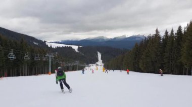 Ukrayna Karpatya dağlarındaki Bukovel kayak merkezinin karlı yamacında kayak yapan insanlar. 