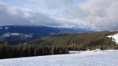 Bukovel kayak merkezinin zirvesinden, Ukrayna Karpatları. Karlı dağ sırtı, köknar ormanı ve küçük ahşap evlerin güzel kış manzarası..