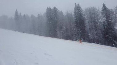 Ukrayna Karpatya dağlarındaki Bukovel kayak merkezinin karlı yamacında kayak yapan kişi. Kar yağışı sahnesi, kar fırtınası, soğuk hava.