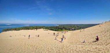 La Teste-de-Buch, Arcachon Körfezi, Fransa - 09 Mayıs 2024: Avrupa 'nın en uzun kum tepesi olan Pilat' ın engin kumulunun panoramik manzarası. Turistler ve çam ormanlarıyla benekli devasa altın kumsallar.