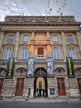 Paris, Fransa - 10 Aralık 2025: Monnaie de Paris 'in (Paris Darphanesi) büyük girişi. Neoklasik cephede uzun sütunlar, karmaşık taş oymalar ve bakır renkli dairesel bir tabela yer alıyor.