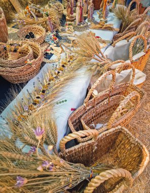 Causeni, Moldova - 27 Temmuz 2025: Bir açık hava pazarında geleneksel kır sanatı. Çeşitli dokunmuş hasır sepetler, karışık buğday kılıfı düzenlemeleri ve ulusal kostümler giymiş el yapımı halk bebekleri.