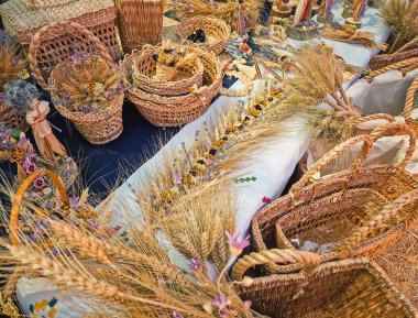 Causeni, Moldova - 27 Temmuz 2025: Bir açık hava pazarında geleneksel kır sanatı. Çeşitli dokunmuş hasır sepetler, karışık buğday kılıfı düzenlemeleri ve ulusal kostümler giymiş el yapımı halk bebekleri.