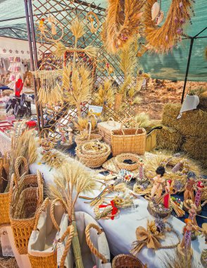 Causeni, Moldova - 27 Temmuz 2025: Bir açık hava pazarında geleneksel kır sanatı. Çeşitli dokunmuş hasır sepetler, karışık buğday kılıfı düzenlemeleri ve ulusal kostümler giymiş el yapımı halk bebekleri.