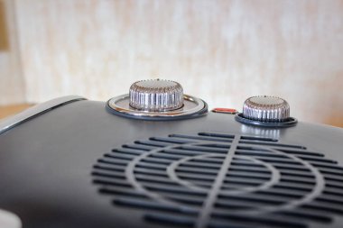 Mavi, retro-stil elektrikli fan ısıtıcısının yakın çekim görüntüsü krom detaylar ve iki kontrol düğmesi olan ahşap bir yüzeye oturur..