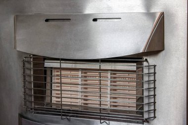 Taşınabilir paslanmaz çelik bir iç gaz ısıtıcısının yakın çekimi seramik kızılötesi ısıtma elementleri koruyucu bir kablo kafesinden görülebiliyor, sağ altta kontroller var..