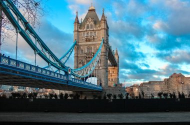 Londra, Birleşik Krallık - 25 Aralık 2025: Tower Bridge Thames üzerinde bulutlu bir gökyüzünün altında duruyor. İkonik Viktorya dönemi Gotik kuleleri ve mavi süspansiyon kabloları Londra 'nın modern siluetini çerçeveliyor..