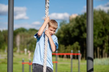 Aktif genç çocuk açık hava spor sahasında ip tırmanışı, spor konsepti, güç ve sağlıklı yaşam tarzı