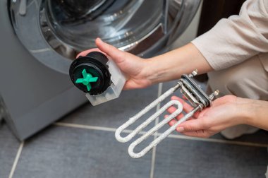 Kireçle kaplı bir ısıtma elementi ve tamir ve bakım sırasında çamaşır makinesinin pompasını tutan kişi, cihaz bakımını ve temizlik sürecini gösteriyor