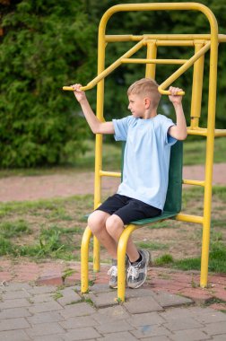Aktif sarışın genç, yeşil bir parkta sarı spor aletleriyle antrenman yapıyor. Fiziksel aktivitelerden ve taze ai 'den zevk alıyor.