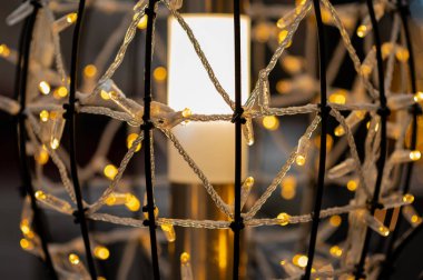 Sıcak festival ışıklarına sarılı sanatsal metal küre şık bir tatil ortamı yaratıyor.