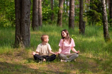 Anne ve oğlu nilüfer çiçekli ormanda poz veriyor, temizliyor, birbirlerine gülümsüyor ve doğada neşeli bir anı paylaşıyorlar.
