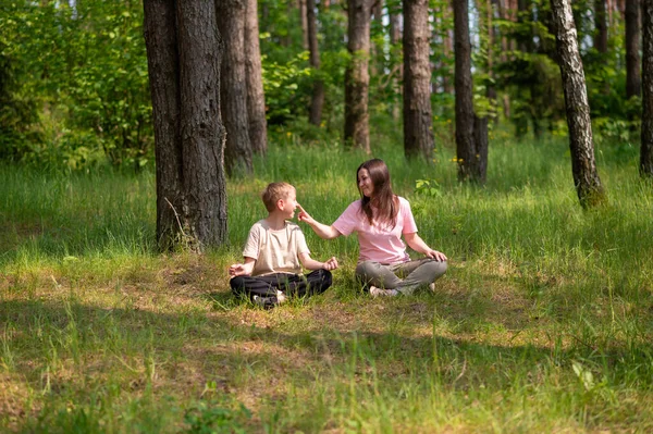 Anne ve oğlu nilüfer çiçekleri içinde meditasyon yapıyor ve gülüyor. Orman çayırlarında poz veriyor, birlikte doğanın ve zamanın tadını çıkarıyor.