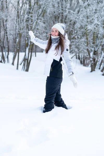 Sıcak kış giysileri içinde genç bir kadın karlı bir ormanda duruyor ve sessizliğin, temiz havanın ve huzurlu kış doğasının tadını çıkarıyor.