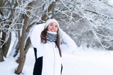 Karlı kış parkında örgü ören genç bir kadın. Sıcak kış yaşam tarzı, soğuk hava, açık hava portresi ve mevsimsel konfor
