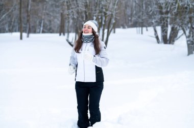 Kışın karla kaplı bir parkta koşan bir kadın. Açık hava kardiyo çalışması, kış koşusu, dayanıklılık eğitimi, soğuk hava kondisyonu ve aktif sağlıklı yaşam tarzı konsepti.