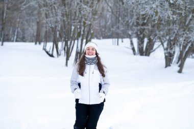 Kışın karla kaplı bir parkta koşan bir kadın. Açık hava kardiyo çalışması, kış koşusu, dayanıklılık eğitimi, soğuk hava kondisyonu ve aktif sağlıklı yaşam tarzı konsepti.