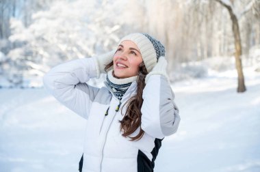 Kışlık ceketli ve örgü şapkalı neşeli kadın soğuk havanın, özgürlük, neşe ve kış yaşam tarzının tadını çıkarıyor.