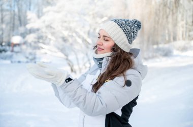 Kış parkında karla oynayan gülümseyen kadın, eğlence konsepti, kaygısız yaşam tarzı ve mevsimsel mutluluk.