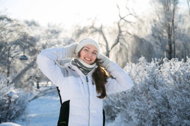 Karlı ormanda sıcak kıyafetler giyen gülümseyen kadın portresi, mutluluk kavramı, doğa ve kış yaşam tarzı.