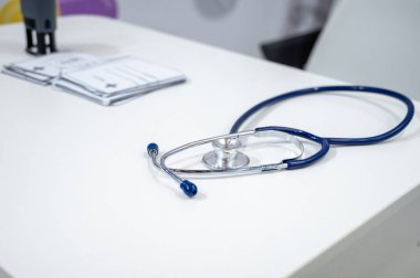 Profesyonel mavi steteskopun yakın plan bir fotoğrafı bir yığın tıbbi belge ve bir ofis pulunun yanında duruyor. Sağlık yönetimi, sağlık sigortası ve hastane rutini kavramı