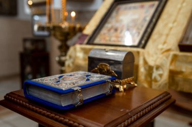 Ortodoks katedralinin dini sembolleriyle süslü metal kabartma ve gümüş sandıklı mavi kadife İncil kitabı ve bulanık kilise arka grubuna olan inanç.